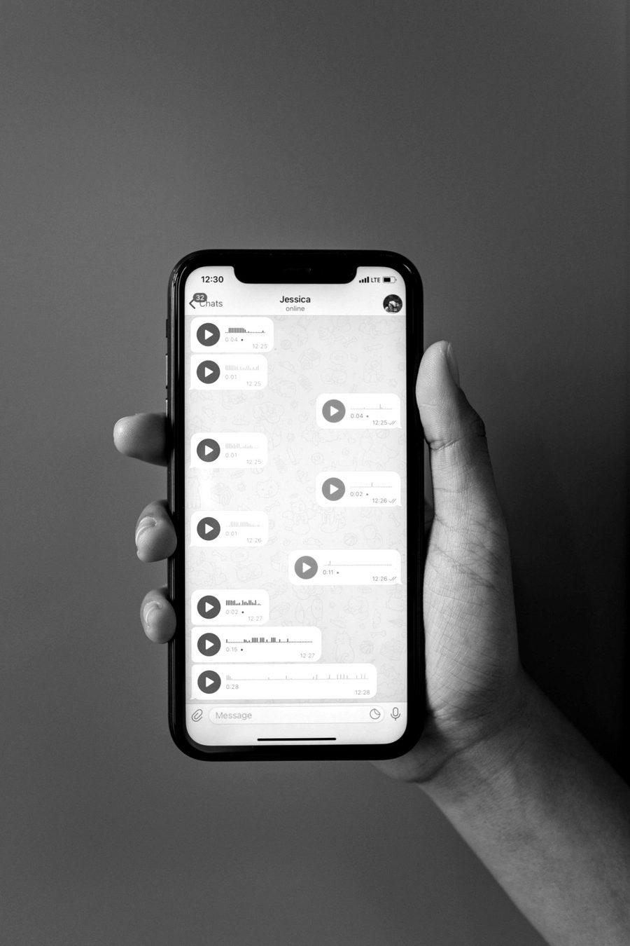 Mão segurando um celular com várias mensagens de áudio sem resposta no WhatsApp